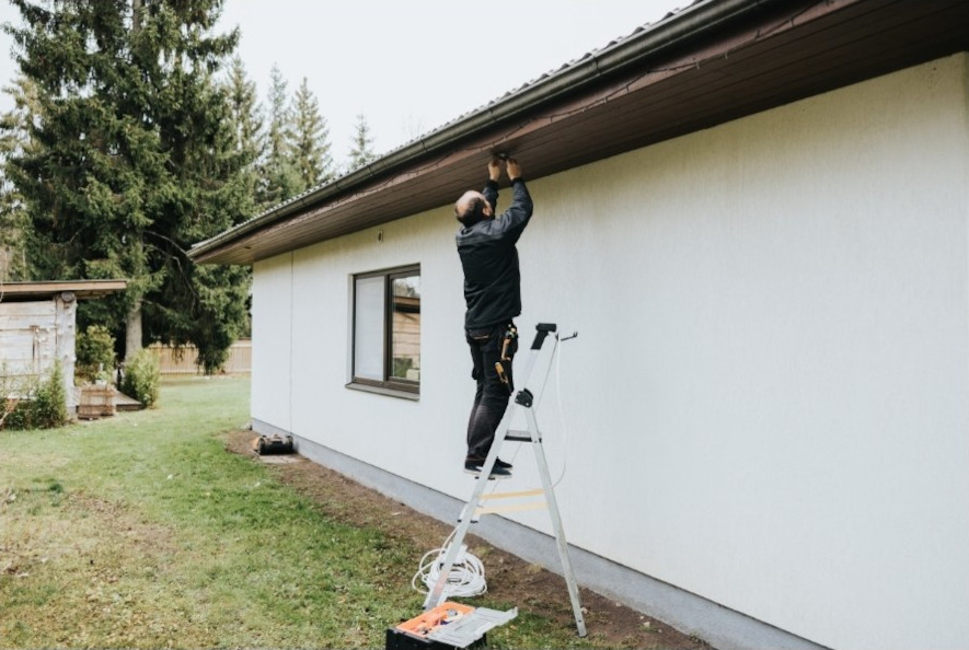 Elektriker installerer belysning på takfoten til en enebolig